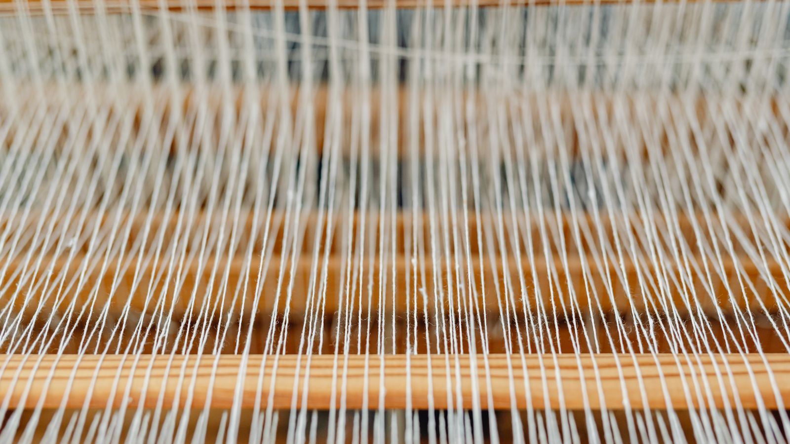 A hand-loomed tweed weave seen close, warp crossing weft